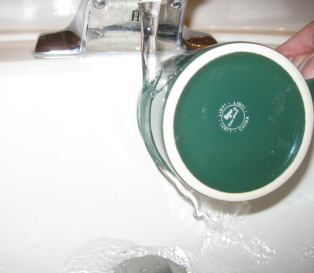A stream of water from a faucet being diverted to side after it touch a drinking cup